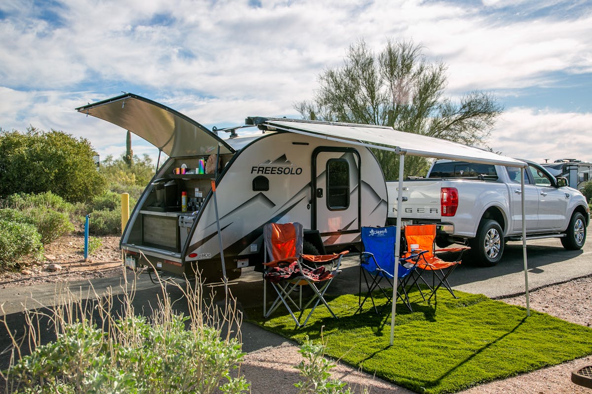Freesolo motorhome set up at a desert campsite with camping chairs and awning extended, a classic boondocking scene