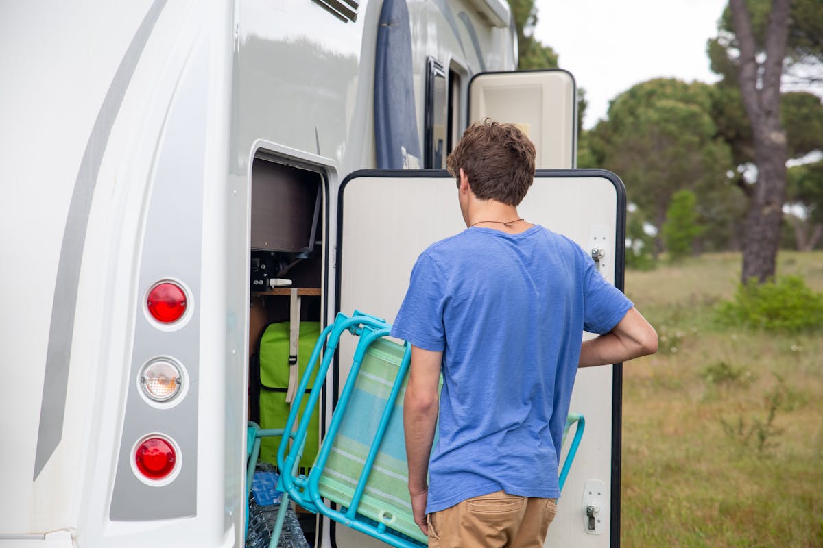 A man loads camping gear into an RV, preparing for an outdoor adventure