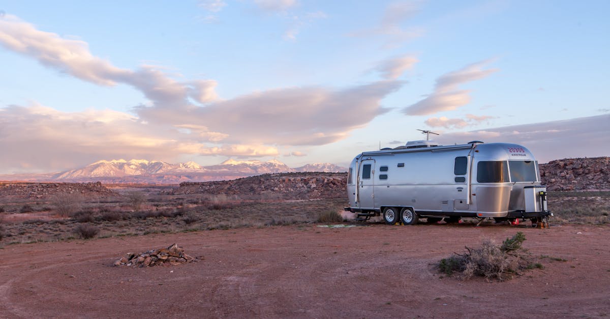 Silver Airstream trailer dry camping in a desert landscape with snow-capped mountains at sunset