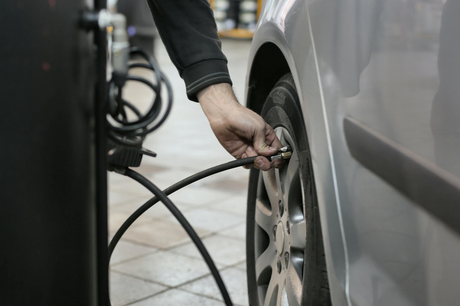 Mechanic checking tire pressure with a gauge inside an auto repair shop