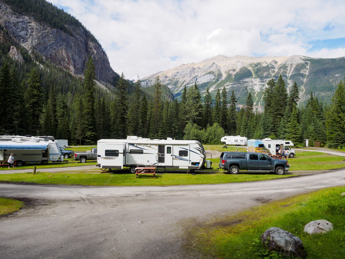 RVs and travel trailers at a scenic mountain campsite surrounded by lush forest